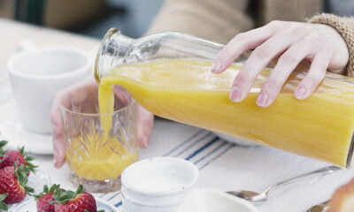 Cropped view of woman pouring orange juice from bottle into glass